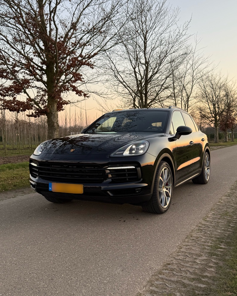 Zwarte Porsche Cayenne vooraanzicht bij zonsondergang